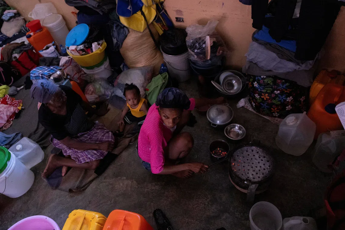 A woman displaced by gang war violence cooks inside a classroom at the Darius Denis school, which has been turned into a shelter, in Port-au-Prince, Haiti May 5, 2024. REUTERS/Ricardo Arduengo