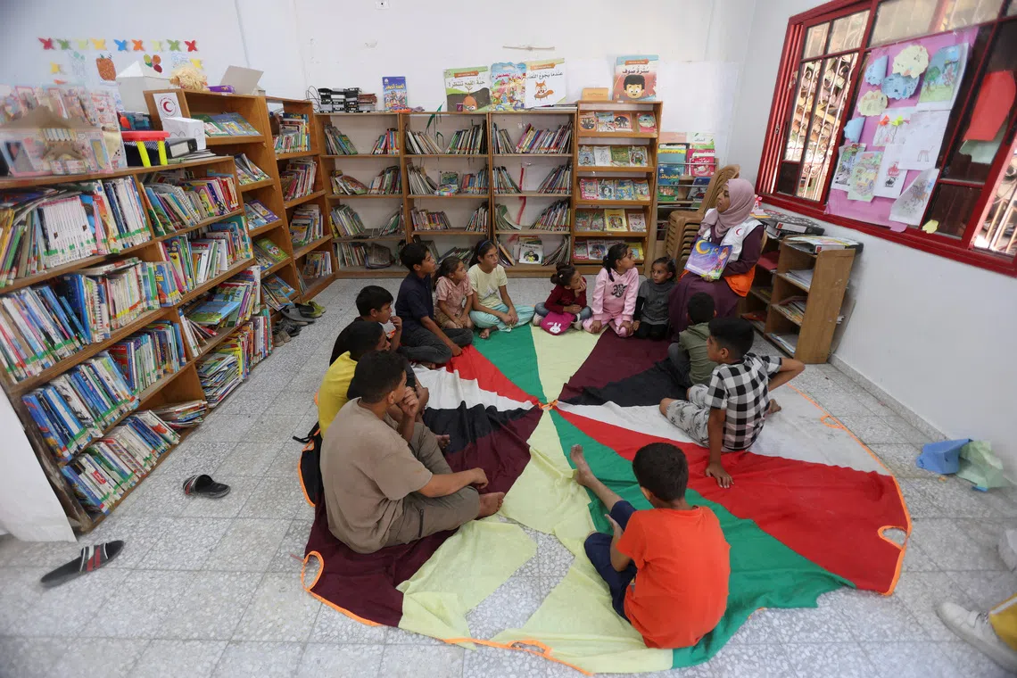 A member of the Palestinian Red Crescent Society reads a story to children as part of mental support activities at the organization’s centre, in Khan Younis in the southern Gaza Strip, October 30, 2025. REUTERS/Ramadan Abed