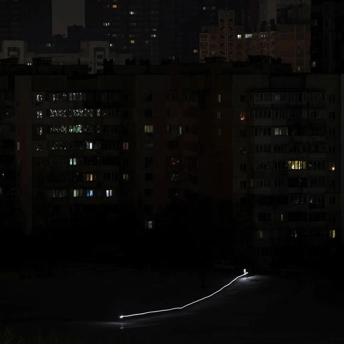 Children use a flashlight as they slide down a snow slope during a power blackout after critical civil infrastructure was hit by Russian missile and drone attacks, amid Russia's attack on Ukraine, in Kyiv, Ukraine January 20, 2026. Picture taken with long exposure. REUTERS/Vladyslav Sodel