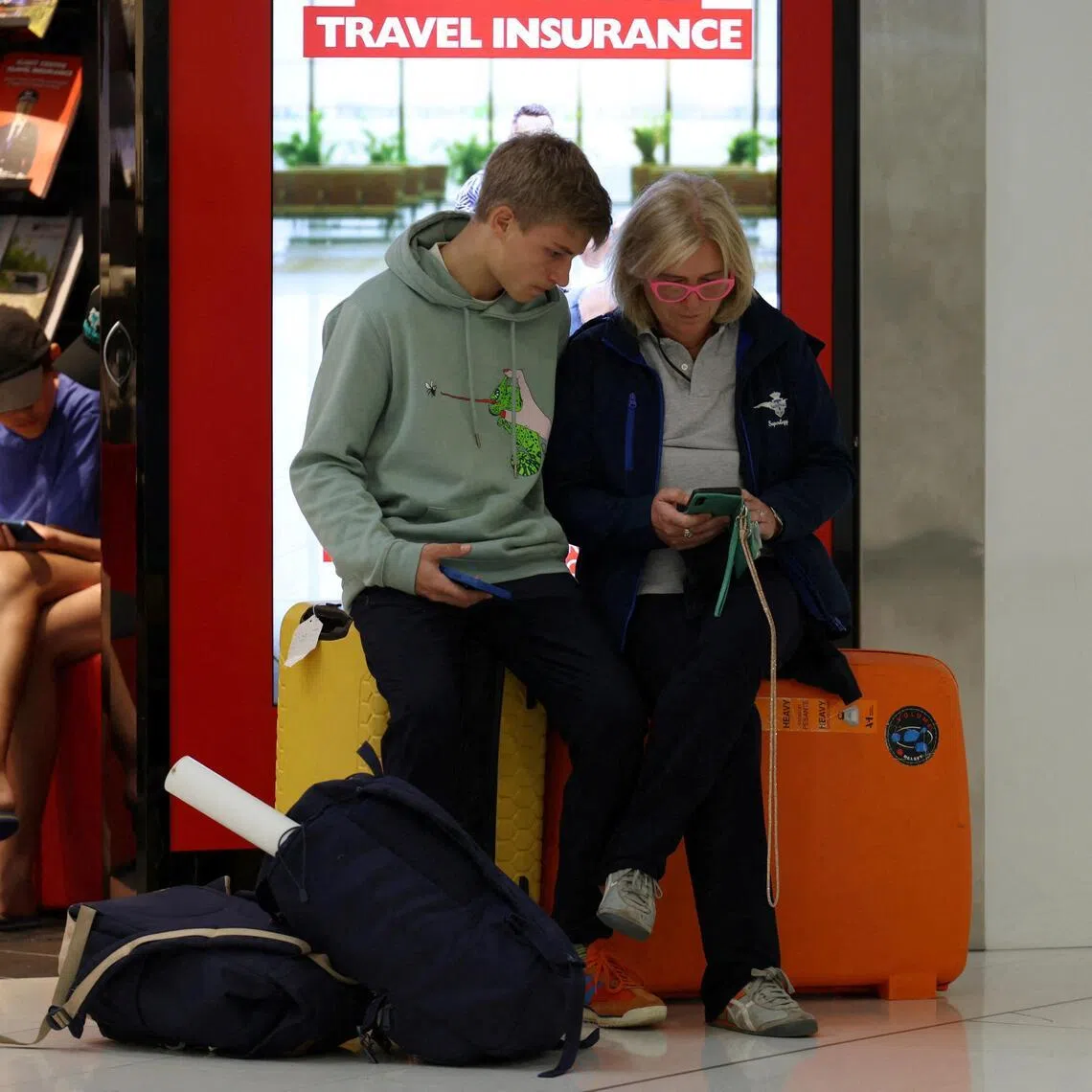Stranded traveller Alessandra Giorgetti and her son Ascanio book an alternative flight to Milan after their Qatar flight via Doha was cancelled at Sydney Airport.