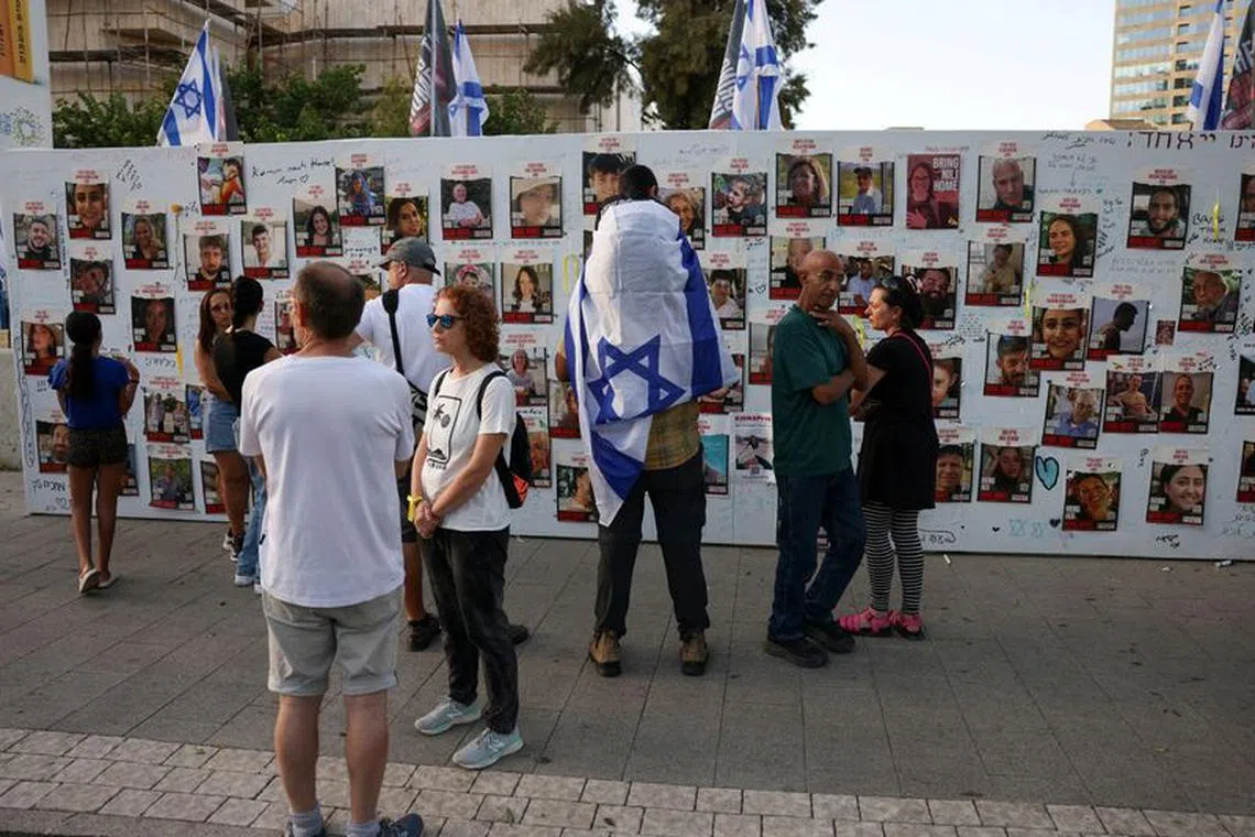 FILE PHOTO: People stand next to the wall with pictures, dedicated to hostages that are being held in Gaza after they were kidnapped from Israel by Hamas gunmen on October 7, as families and supporters of hostages hold a demonstration calling for their immediate release in Tel Aviv, Israel November 3, 2023. REUTERS/Ronen Zvulun/File Photo
