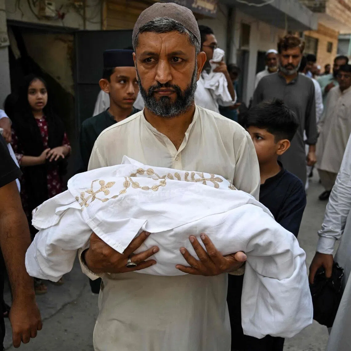 A man carries the body of a newborn child who died following a fire at a Pakistan hospital on Aug 26.