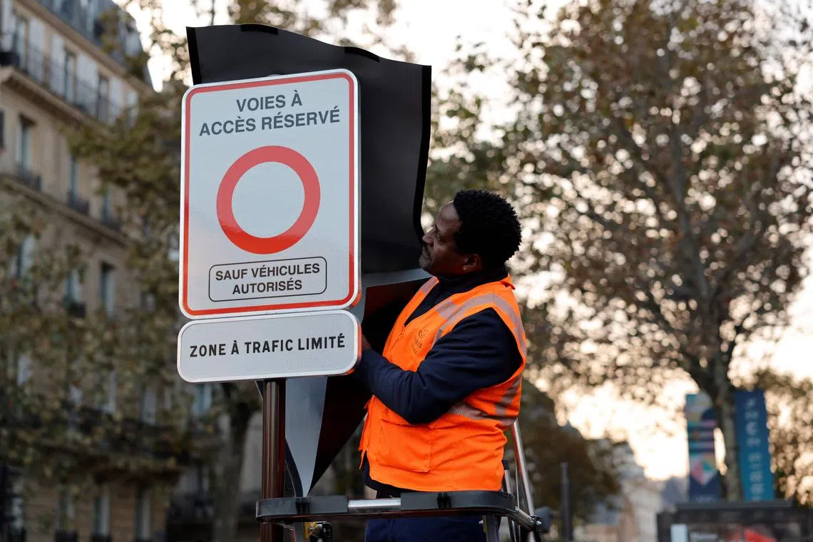 A city employee unveils a traffic sign indicating the limited traffic zone in Paris on Nov 4.