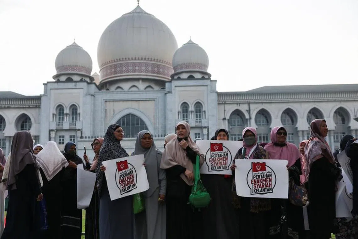 Muslim women hold placards as they stand in protest outside the Palace of Justice on the day the country's federal court delivers verdict in a constitutional case challenging the legality of some Islamic laws in Kelantan state, in Putrajaya, Malaysia February 9, 2024. REUTERS/Hasnoor Hussain