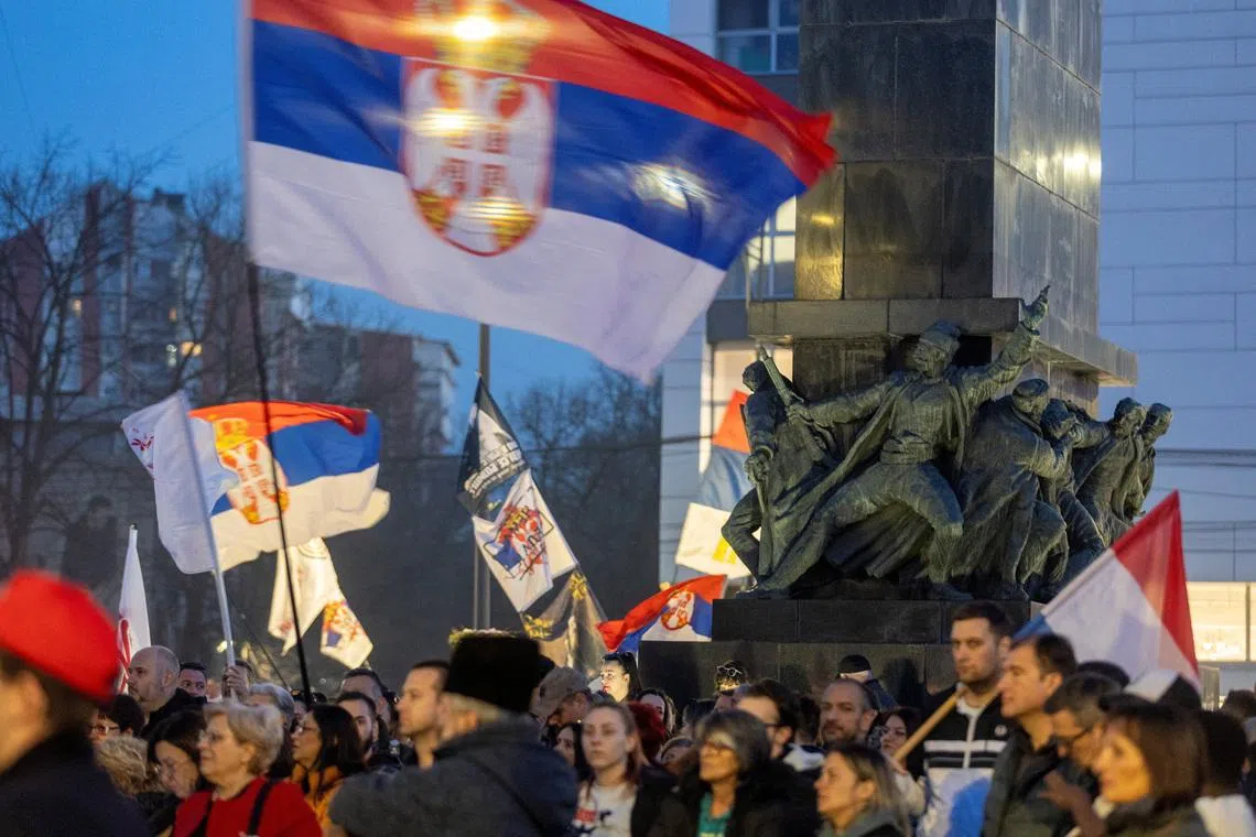 People hold flags during a student-led demonstration to mark one year since a major anti-government rally and to protest against authorities over corruption and accountability, in Nis, Serbia, March 1, 2026. REUTERS/Djordje Kojadinovic