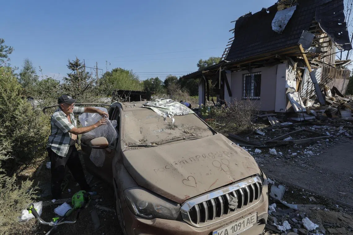 A man covering a broken window of his car following a Russian missile strike at a village outside the Ukrainian capital, Kyiv, on Aug 18.