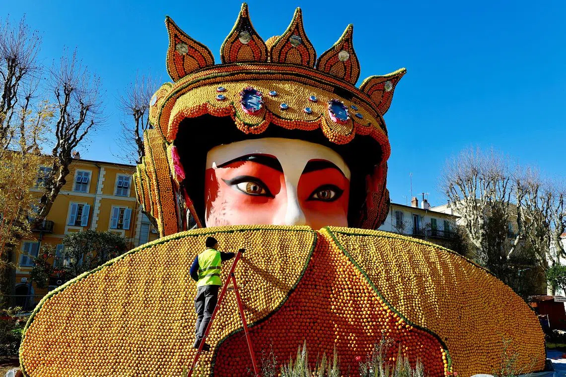 A worker puts the final touches on a sculpture made with lemons and oranges named "Beijing Opera" at the 89th Lemon festival around the theme "Rock and Opera" in Menton, France, Feb 8, 2023. 