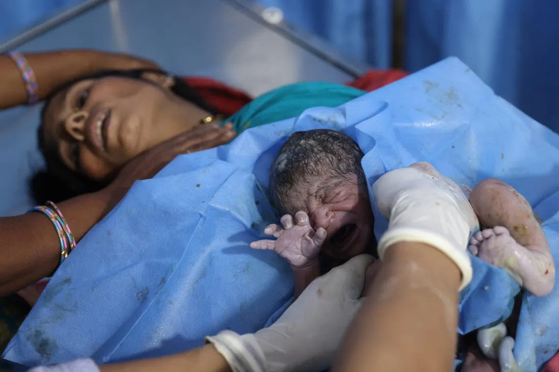 Zamerun Nisha, 33, lying down after giving birth while a doctor holds and cleans her newborn baby, at the labour ward of a community health centre in Bahadurganj subdivision March 21.