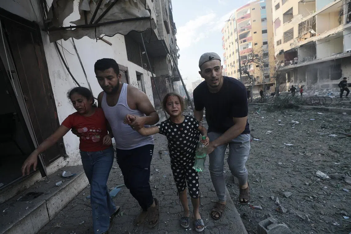 Two men help two wounded young girls leave the area following an Israeli airstrike in Gaza.