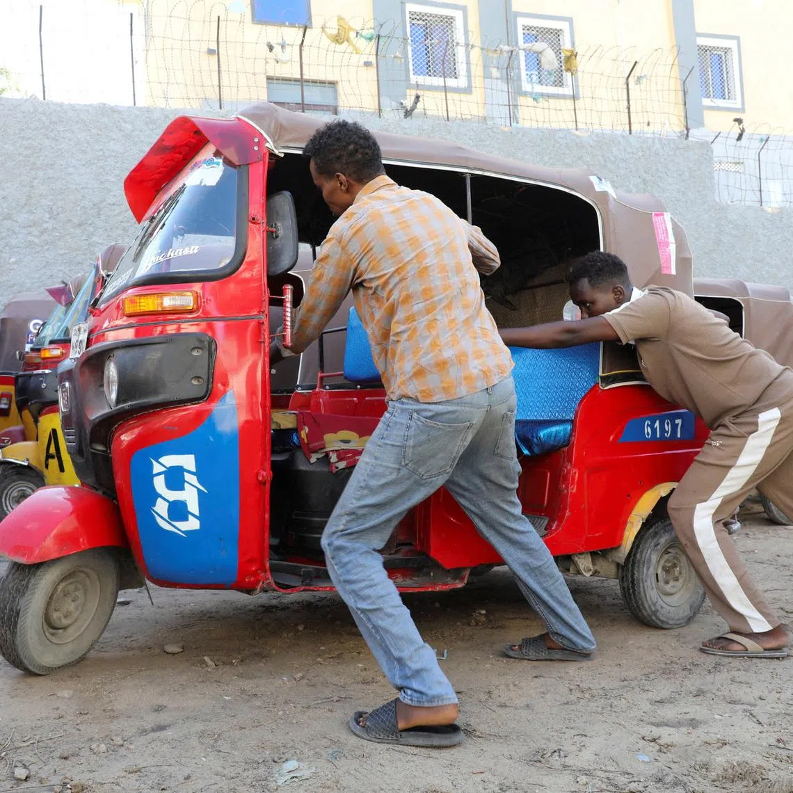 Operators of rickshaw taxis push a vehicle to a parking yard following high fuel prices, amid the U.S.-Israeli conflict with Iran, in Mogadishu, Somalia, March 25, 2026 REUTERS/Feisal Omar