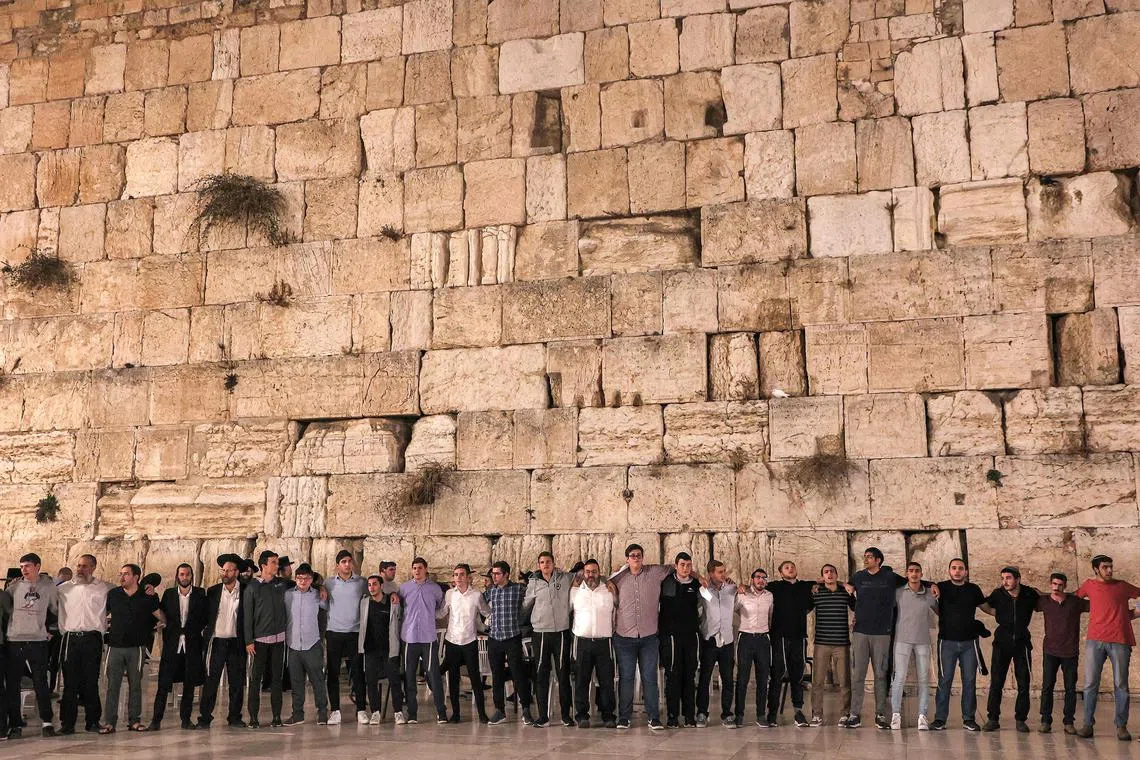 People standing in prayer before the Western Wall, the holiest site where Jews are allowed to pray, in the old city of Jerusalem on Tuesday during a vigil for the victims of the Oct 7 Hamas attack.