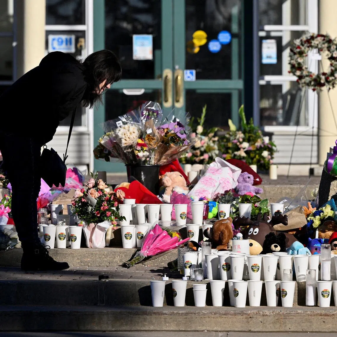 FILE PHOTO: A woman visits a growing makeshift memorial on the steps of the town hall, four days after one of the worst mass shootings in recent Canadian history, in the town of Tumbler Ridge, British Columbia, Canada, February 14, 2026. REUTERS/Jennifer Gauthier/File Photo