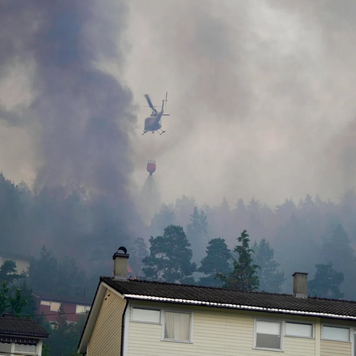 A helicopter dropping water on a huge fire that destroyed more than 100 homes in Drammen, Norway, on July 17.
