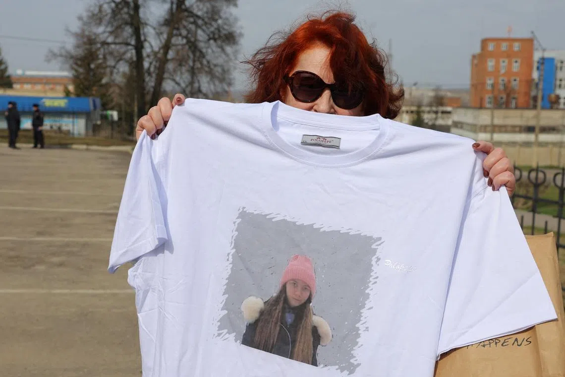 FILE PHOTO: A supporter of Russian citizen Alexei Moskalyov, who was convicted of discrediting the country's armed forces in the course of Russia-Ukraine military conflict, holds a t-shirt with a portrait of Moskalyov's daughter Masha outside a courthouse in the town of Yefremov in the Tula region, Russia, April 6, 2023. REUTERS/Evgenia Novozhenina/File Photo