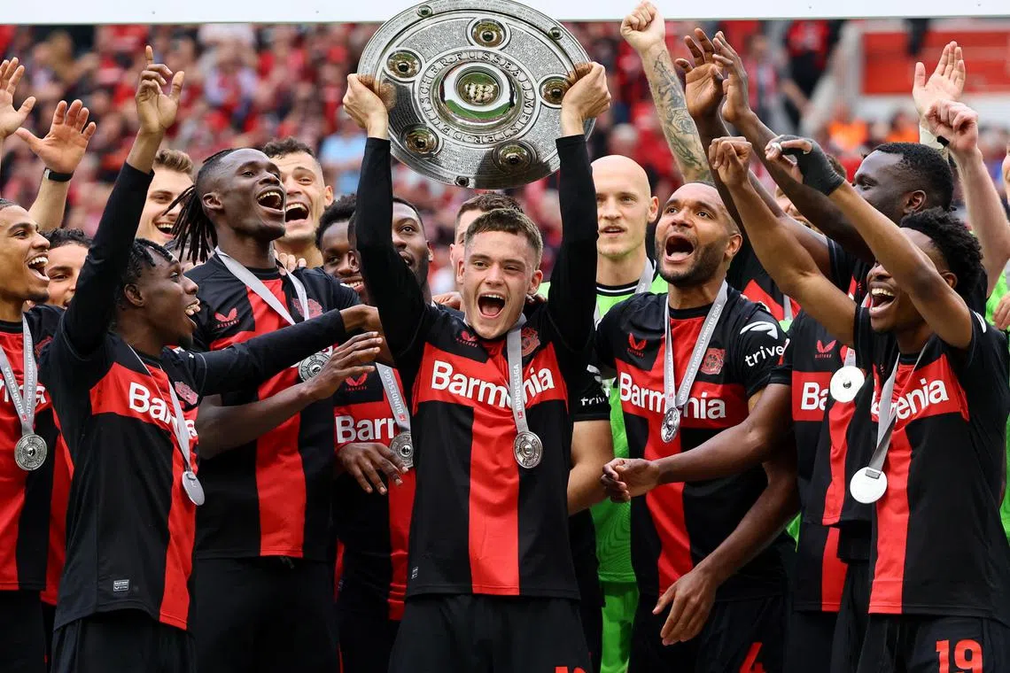 Bayer Leverkusen's Florian Wirtz celebrates with the trophy and teammates after winning the German Bundesliga.