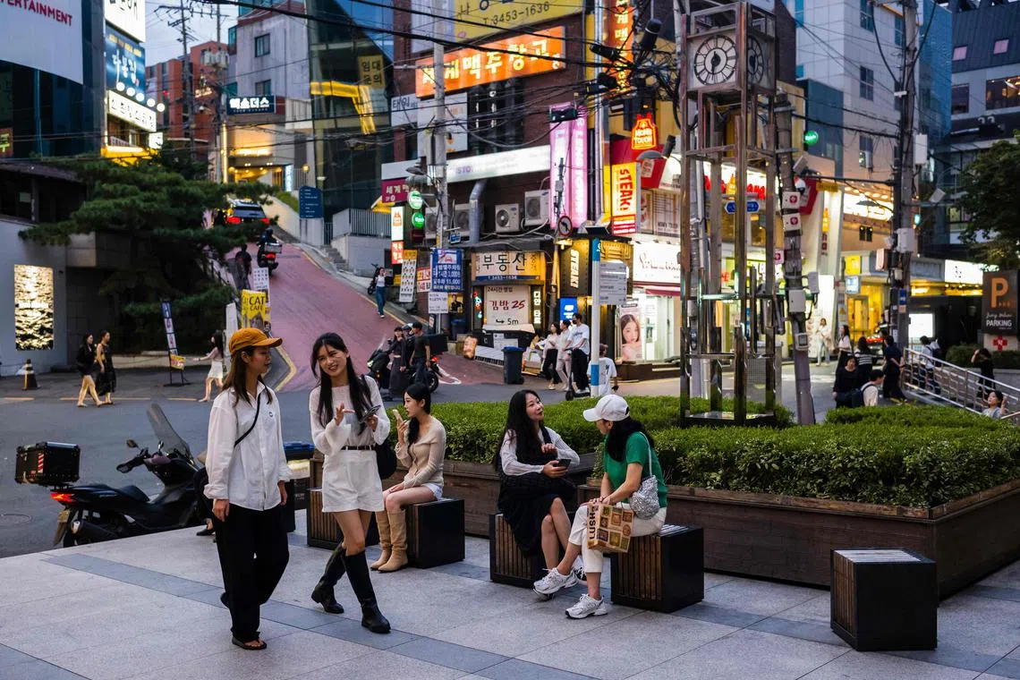 People relax in a seating area near a street in the Gangnam district of Seoul on September 14, 2023. Seoul's Gangnam district, which was made famous by rapper Psy's global hit "Gangnam Style”, is an upscale district known for its luxury boutiques and apartments. (Photo by ANTHONY WALLACE / AFP)