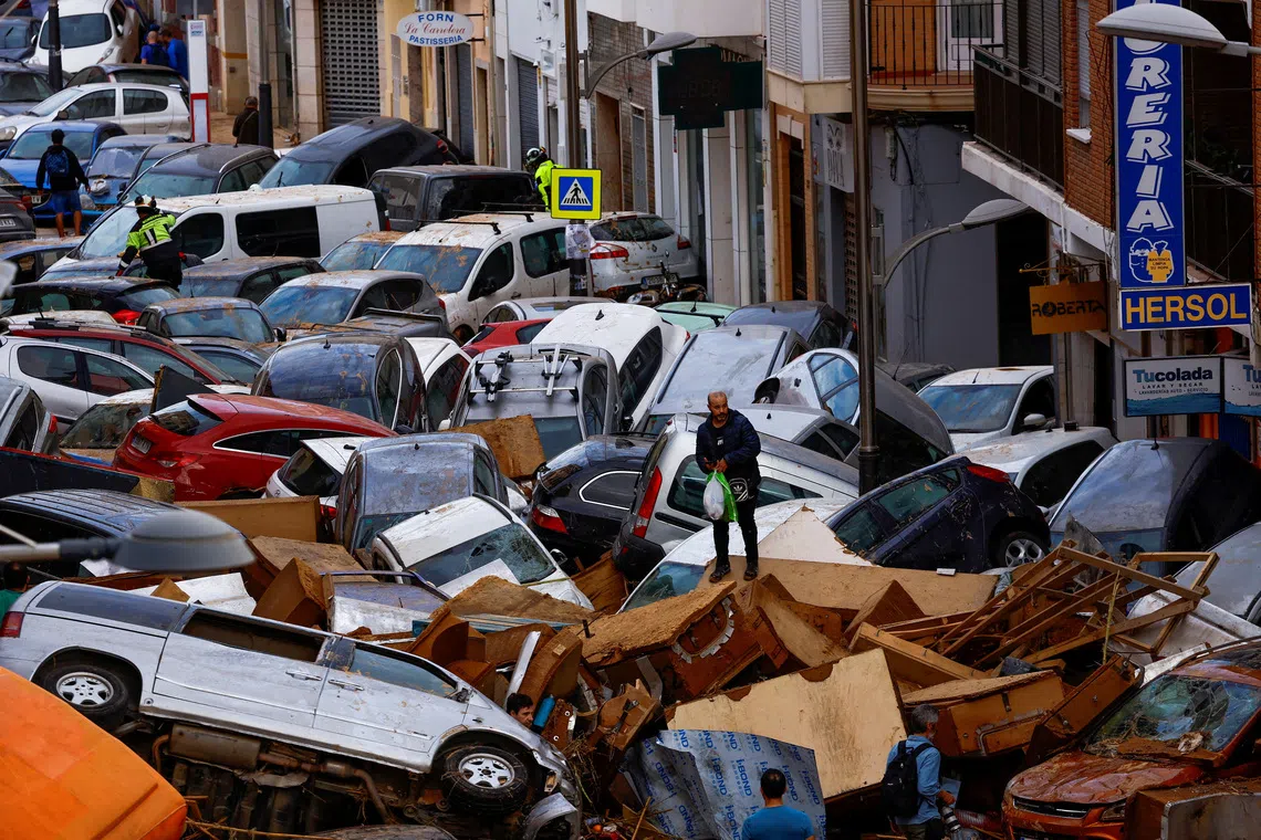 FILE PHOTO: A man stands next to stranded cars, in the aftermath of floods caused by heavy rains, in Sedavi, Valencia, Spain, October 31, 2024. Almost 240 people died in Spain after torrential rains in October 2024 triggered floods that swept through eastern and southeastern Spain. The most severely hit area was Valencia's southern suburbs, where more than 220 people died. REUTERS/Susana Vera/File Photo