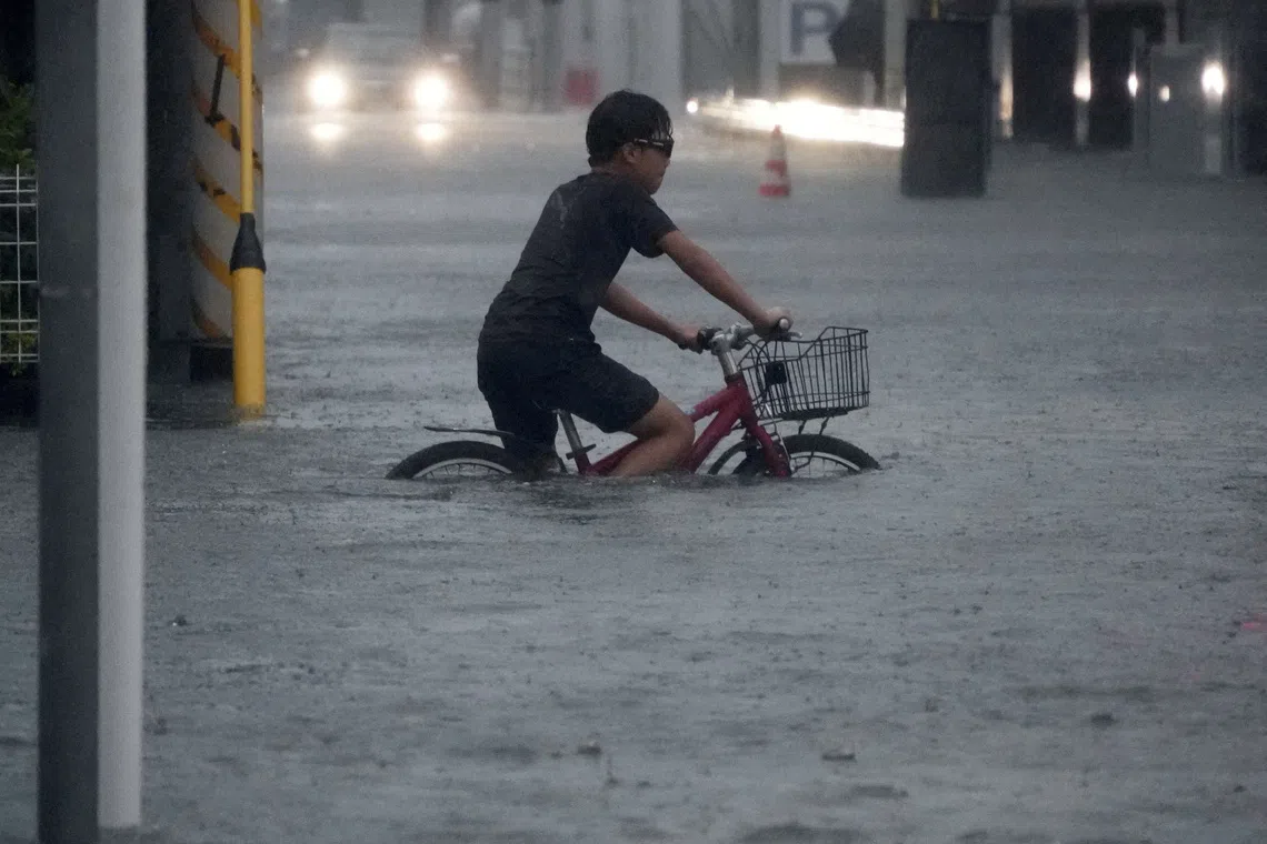 A boy cycles through a flooded street as Typhoon Dujuan brings heavy rain, in Ichikawa, Chiba Prefecture, Japan, September 21, 2026 in this photo taken by Kyodo. Kyodo via REUTERS