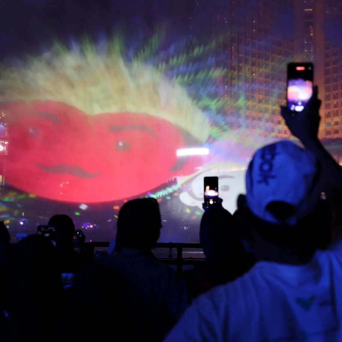 People use their mobile phones as they watch a video mapping show at the Bundaran Hotel Indonesia roundabout while celebrating New Year's Eve in Jakarta, Indonesia, December 31, 2023. REUTERS/Ajeng Dinar Ulfiana