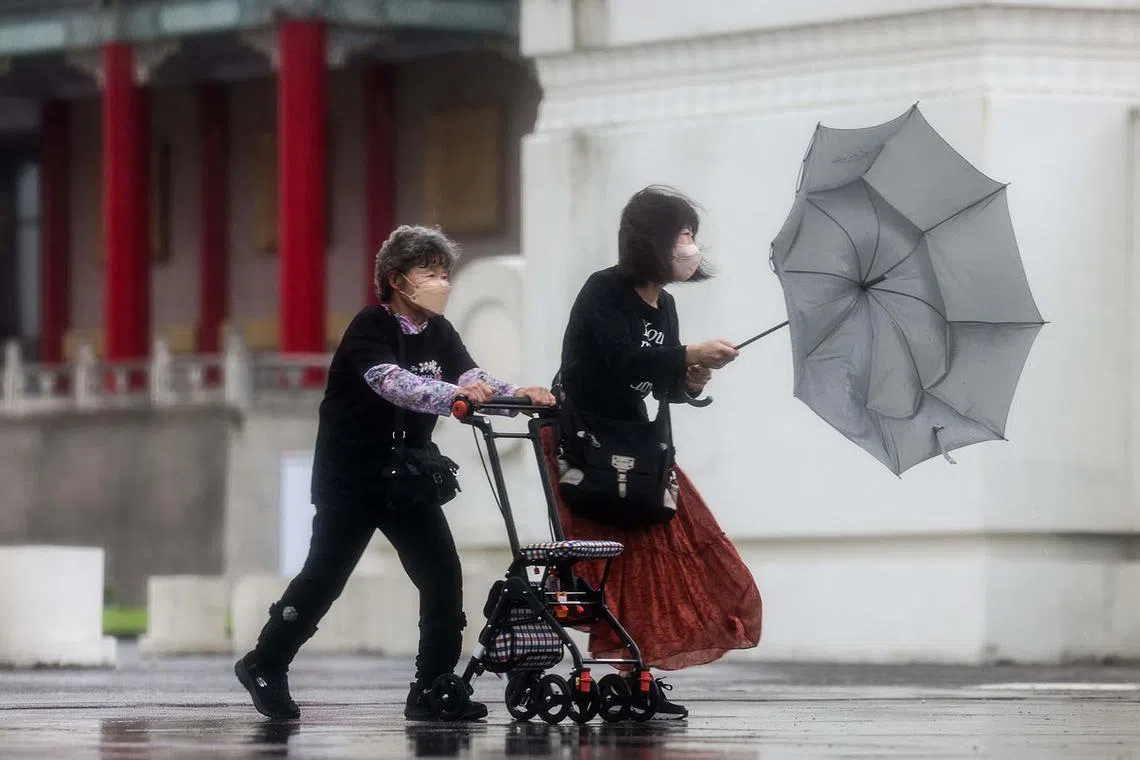 A tourist struggling with an umbrella in strong wind and rain at Chiang Kai Shek memorial hall in Taipei on Nov 12, 2024. 