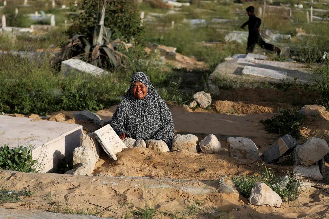 A Palestinian woman visits the grave of her relative at a cemetery, on the first day of Eid al-Fitr that marks the end of the Muslim holy fasting month of Ramadan, in Jabalia, in the northern Gaza Strip March 30, 2025. REUTERS/Mahmoud Issa