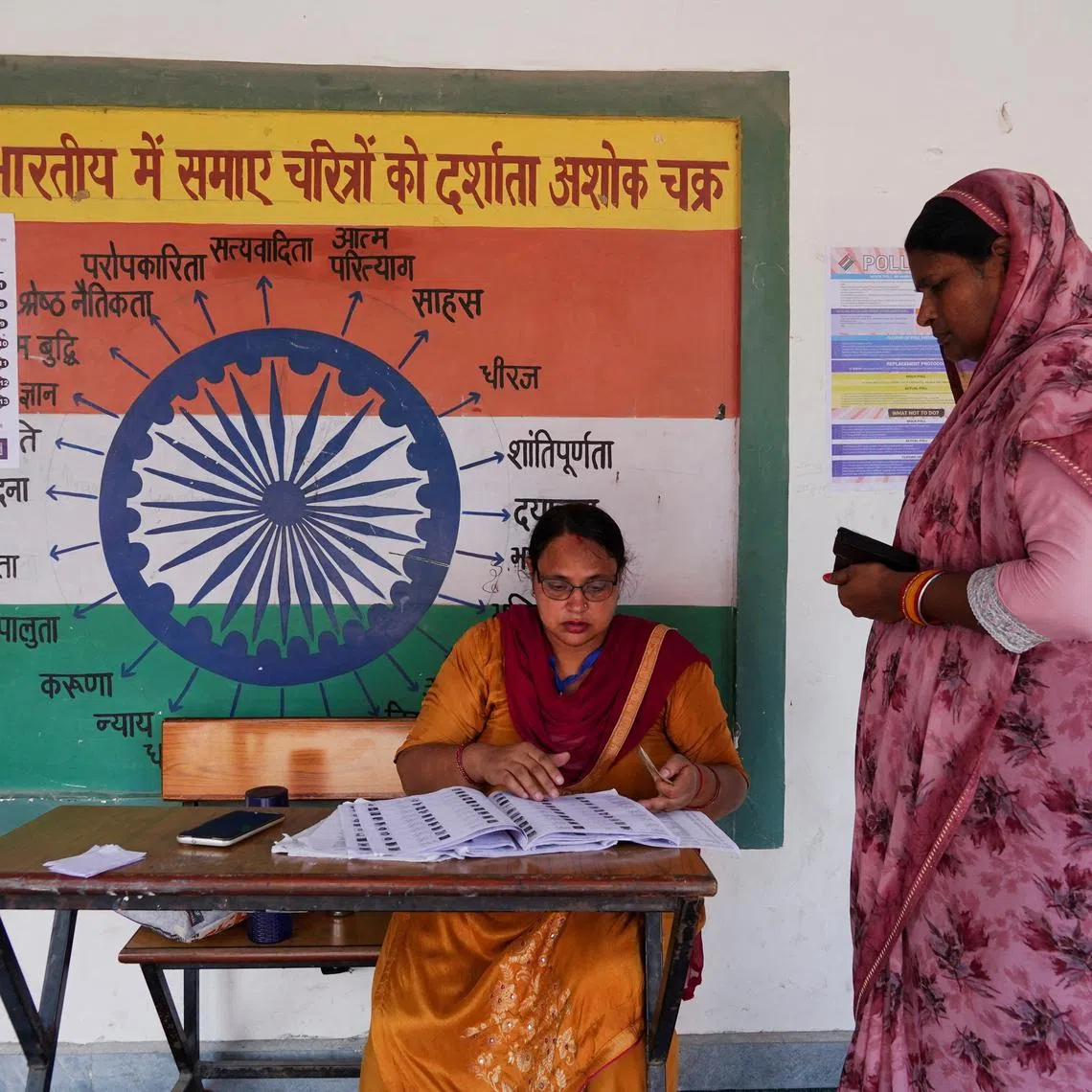 A booth-level officer helps a woman verify her name in the voting list outside a polling station during the state assembly elections, in Karnal, in the northern state of Haryana, India, October 5, 2024. REUTERS/Bhawika Chhabra/File Photo