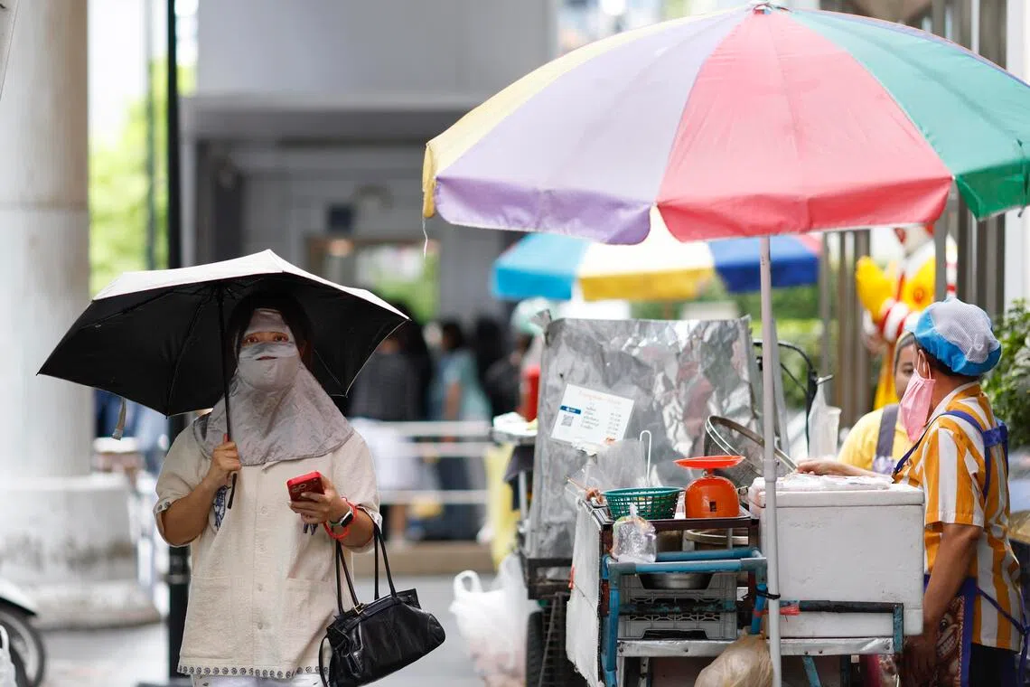 A woman shielding herself from the sun during hot weather at a roadside in Bangkok, Thailand, on March 30.