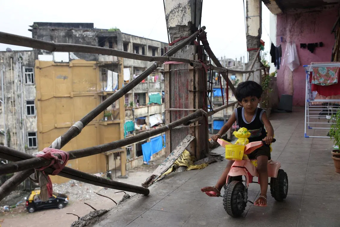 Mrunali, 4, riding a tricycle in the corridor outside her home at the Worli dairy quarters building on Oct 5, 2022.  Inside this crumbling structure, which houses more than 600 people, children play outside their units along corridors with rusted, broken railings held together with rags.
