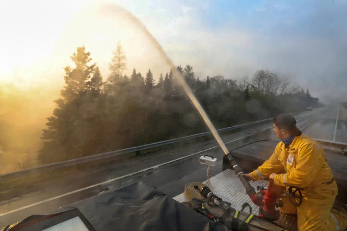 Northfield Fire Department member Seth Slauenwhite sprays down a flare-up along Highway 103 while tackling the Shelburne wildfires in Shelburne County, Nova Scotia, Canada on Friday. 