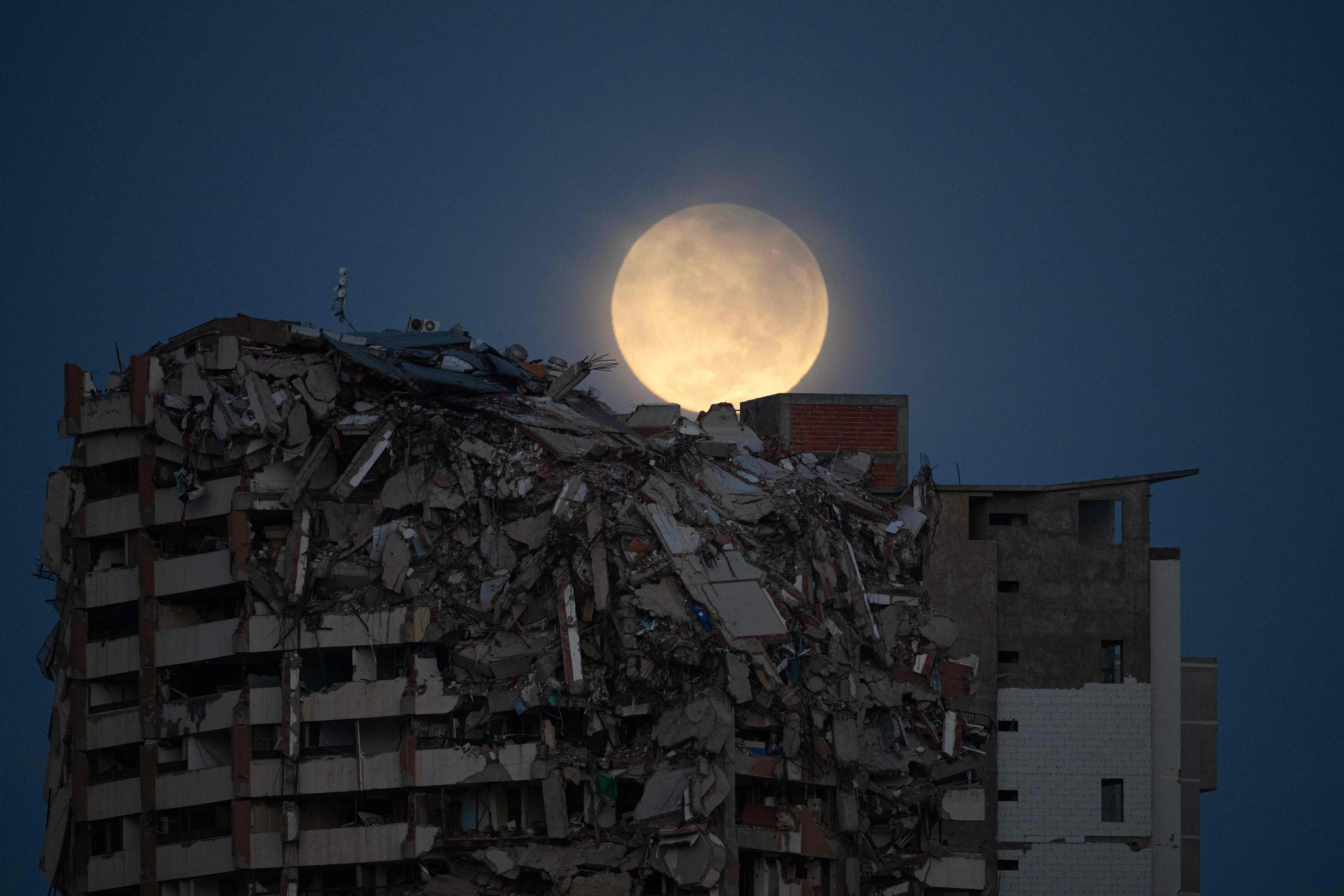 TOPSHOT - A full moon is seen behind a collapsed residential building in Catia La Mar, La Guaira State, Venezuela, on August 28, 2026, over two months after earthquakes of magnitudes 7.2 and 7.5 struck the area. (Photo by Federico PARRA / AFP)
