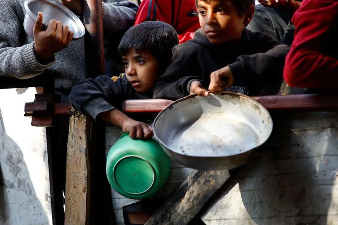 FILE PHOTO: Palestinians wait to receive food cooked by a charity kitchen amid shortages of food supplies, amid the ongoing conflict between Israel and the Palestinian Islamist group Hamas, in Rafah in the southern Gaza Strip, January 16, 2024. REUTERS/Ibraheem Abu Mustafa