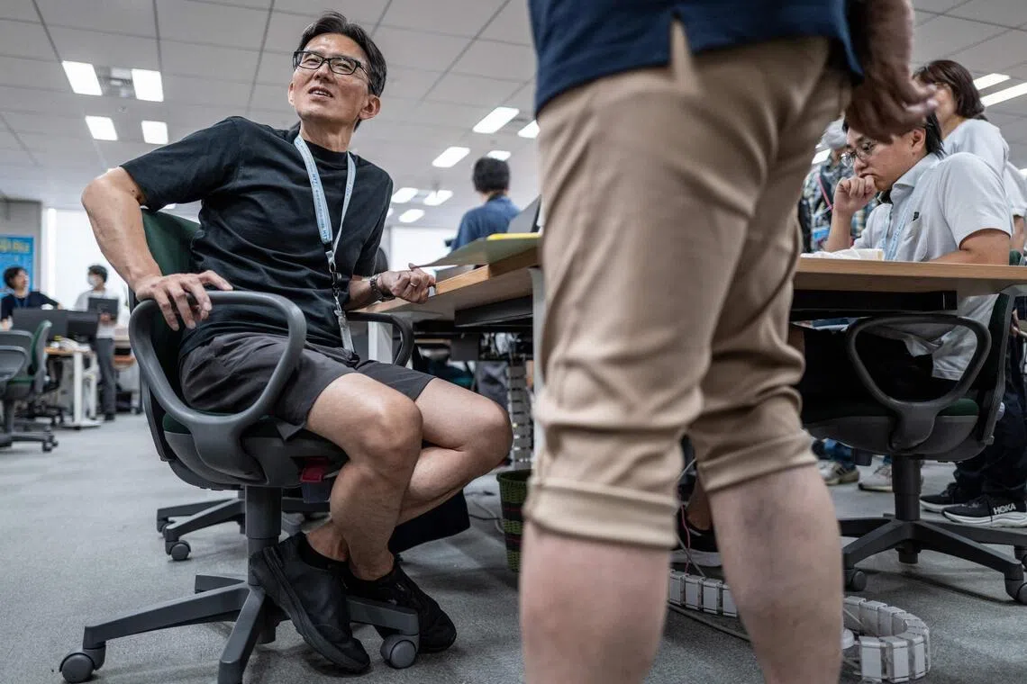Government officials in casual dress code, including shorts, tee shirts and sneakers, work in the office of the Tokyo Metropolitan Government building.
