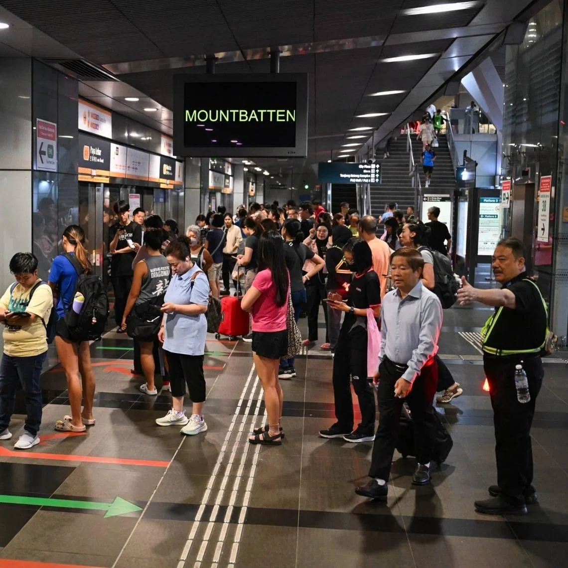 Staff guiding passengers on the platform where they can board the train towards Mountbatten, at Paya Lebar Station.