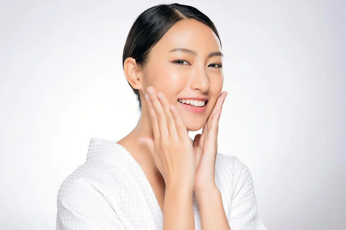 Pretty asian woman touching her face and looking happy