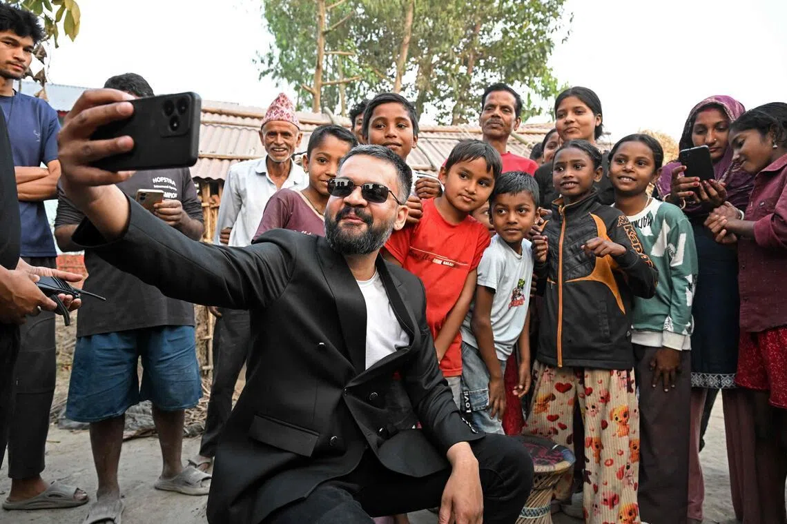 Nepal's PM-to-be Balendra Shah takes a selfie with children and supporters during a door-to-door election campaign at Gauriganj in Jhapa district on Feb 16, 2026.
