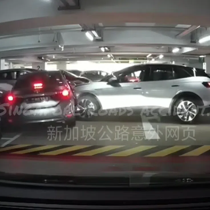 A silver car (right) is seen travelling down a carpark ramp at a high speed.