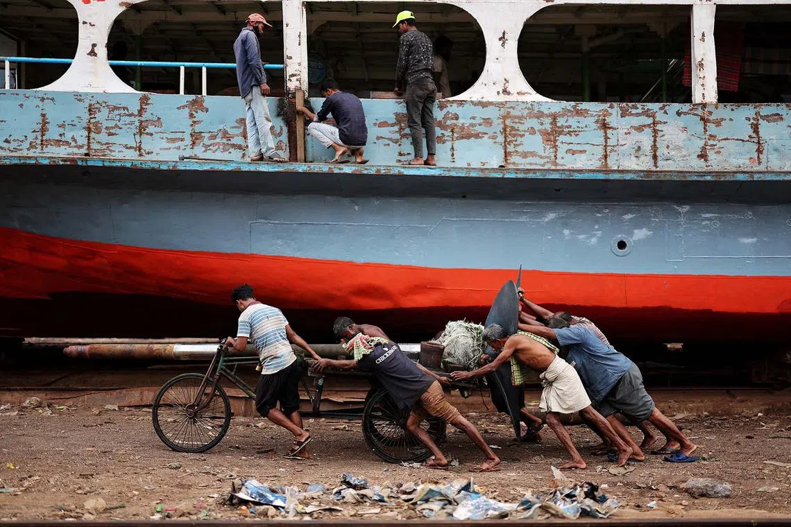 Bangladeshi labourers pulling a cart carrying a ferry propeller in a dockyard in Dhaka, Bangladesh, March 27, 2024. 