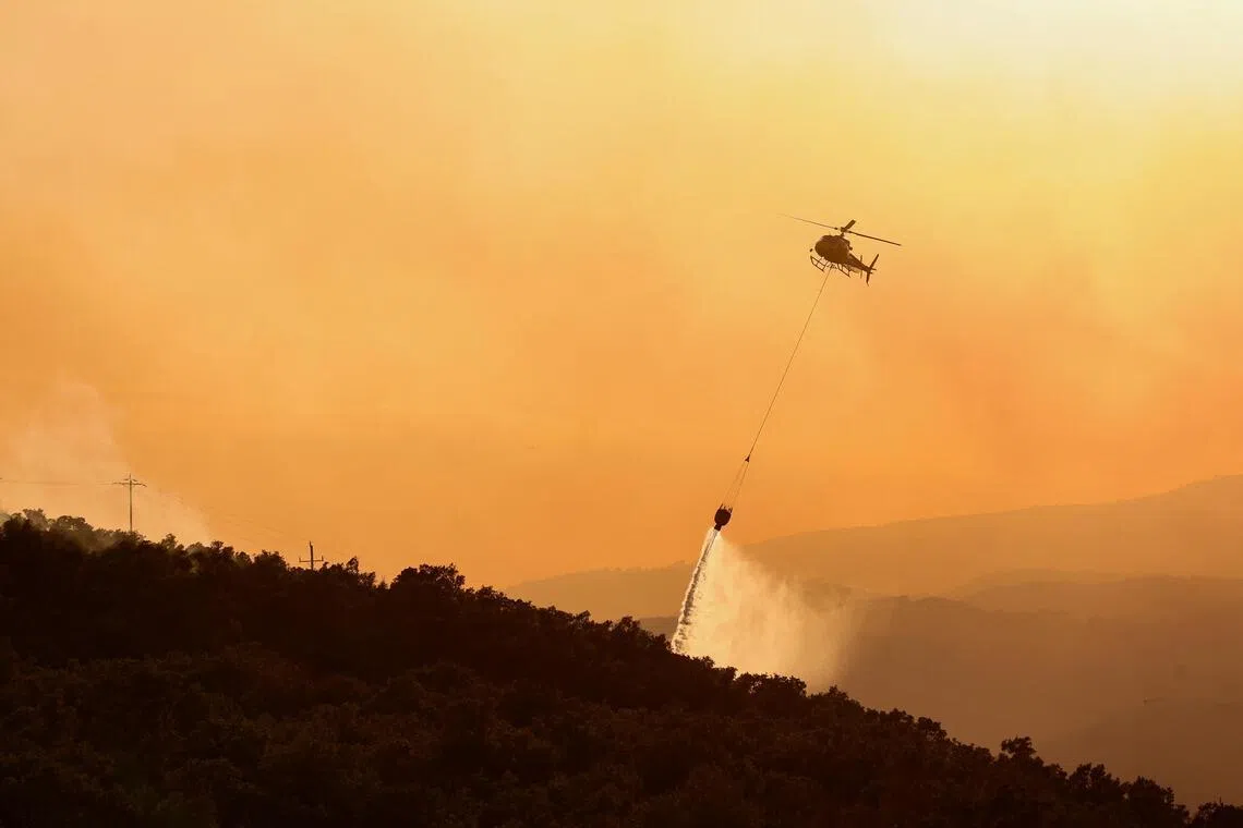 A firefighting helicopter battles a wildfire near Calonge, Spain, July 3, 2026. REUTERS/Bruna Casas