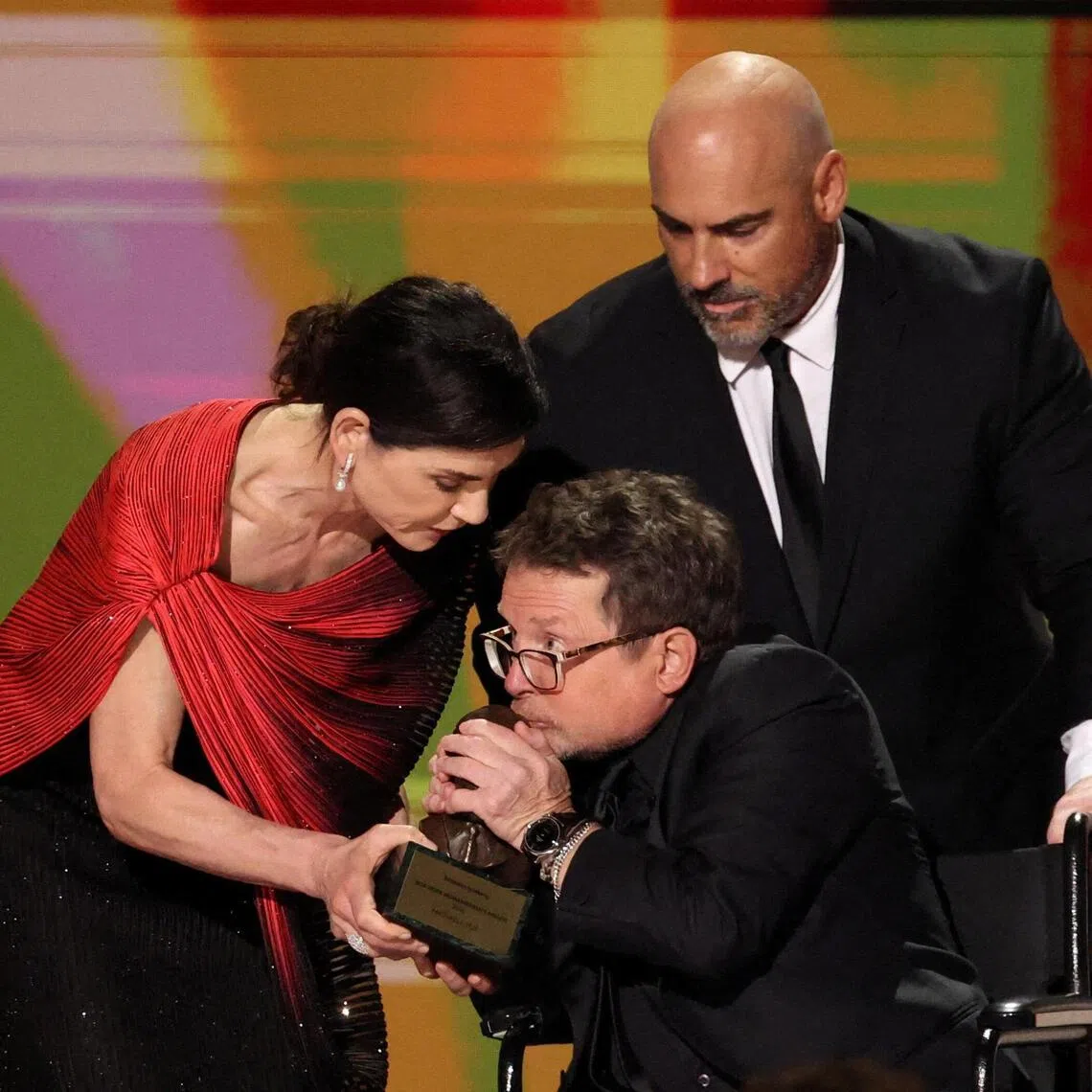 Michael J. Fox was pushed in a wheelchair to accept his award, which he kissed and handed back before he spoke.