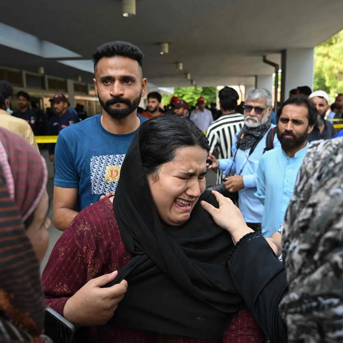 TOPSHOT - Jaweria (C), who said she lost her child in the fire, reacts following a blaze at the Mother and Child Health (MCH) ward of the Pakistan Institute of Medical Sciences (PIMS) Hospital in Islamabad on August 26, 2026. A fire in a maternity ward at a public hospital in the Pakistani capital Islamabad on August 26 morning killed 14 children, a local authority said. (Photo by Aamir QURESHI / AFP)