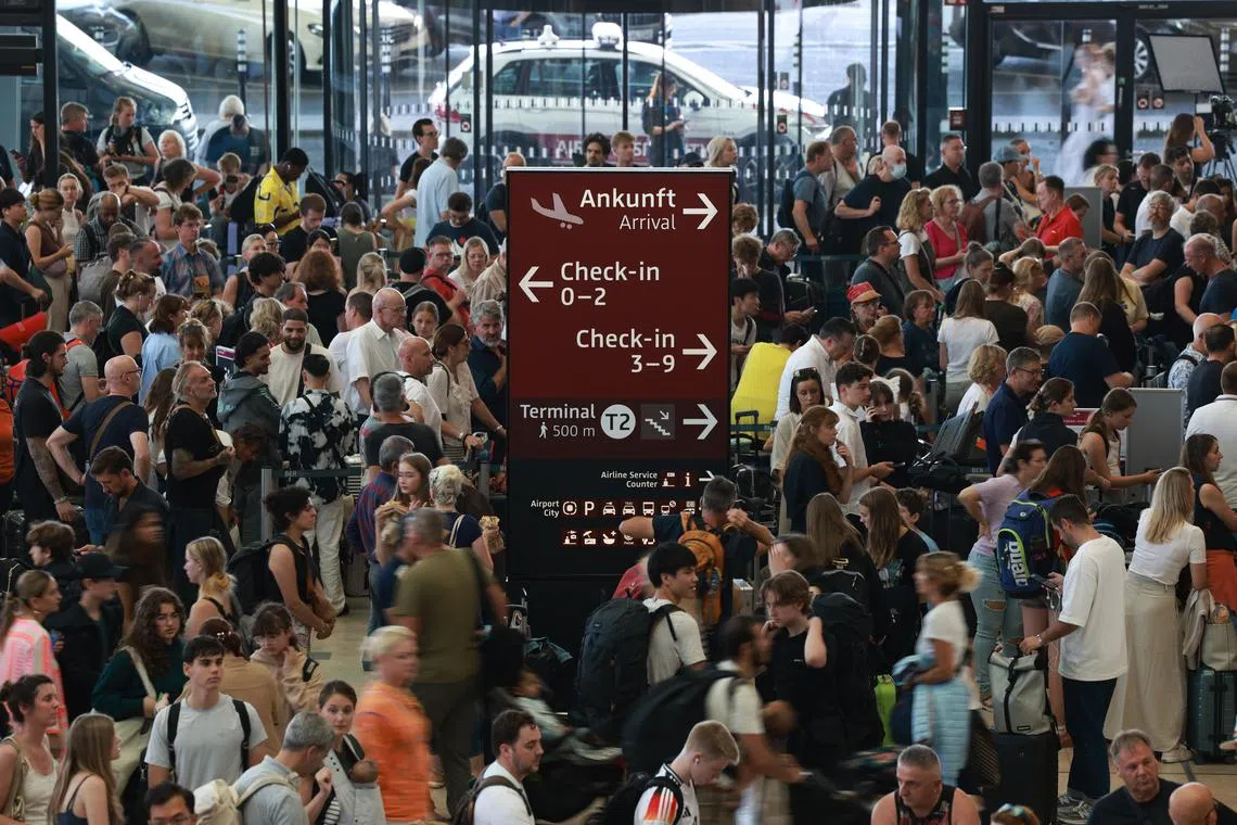 Passengers wait in front of counters at BER Airport in Schoenefeld, Germanyon July 19. BER Airport stated in their 'X' social media account that check-in will be delayed due to a technical fault. 