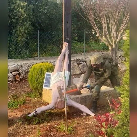 An Israeli soldier damages the head of a statue of Jesus Christ, in Debel, Lebanon, on April 19.