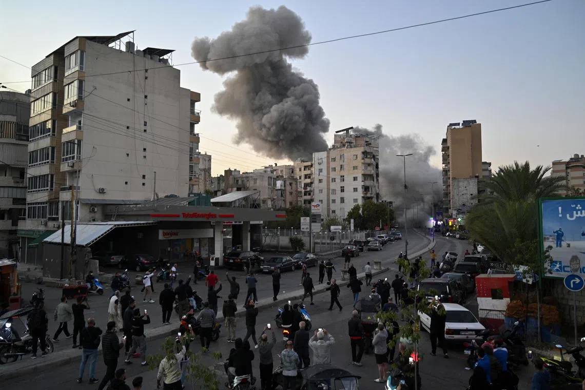 People watching as smoke rises following an Israeli airstrike in southern Beirut, on Nov 14.