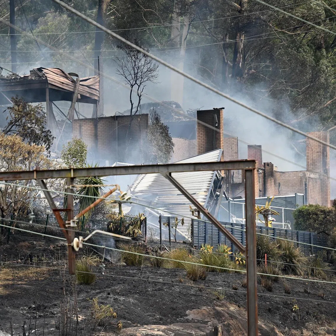 Firefighters mopping up after a bushfire engulfed homes in the Koolewong area in New South Wales, Australia, on Dec 6.