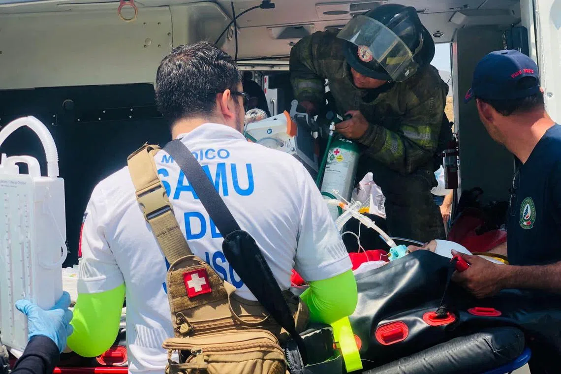 Rescuers move an injured person into an ambulance helicopter, following the bus accident.