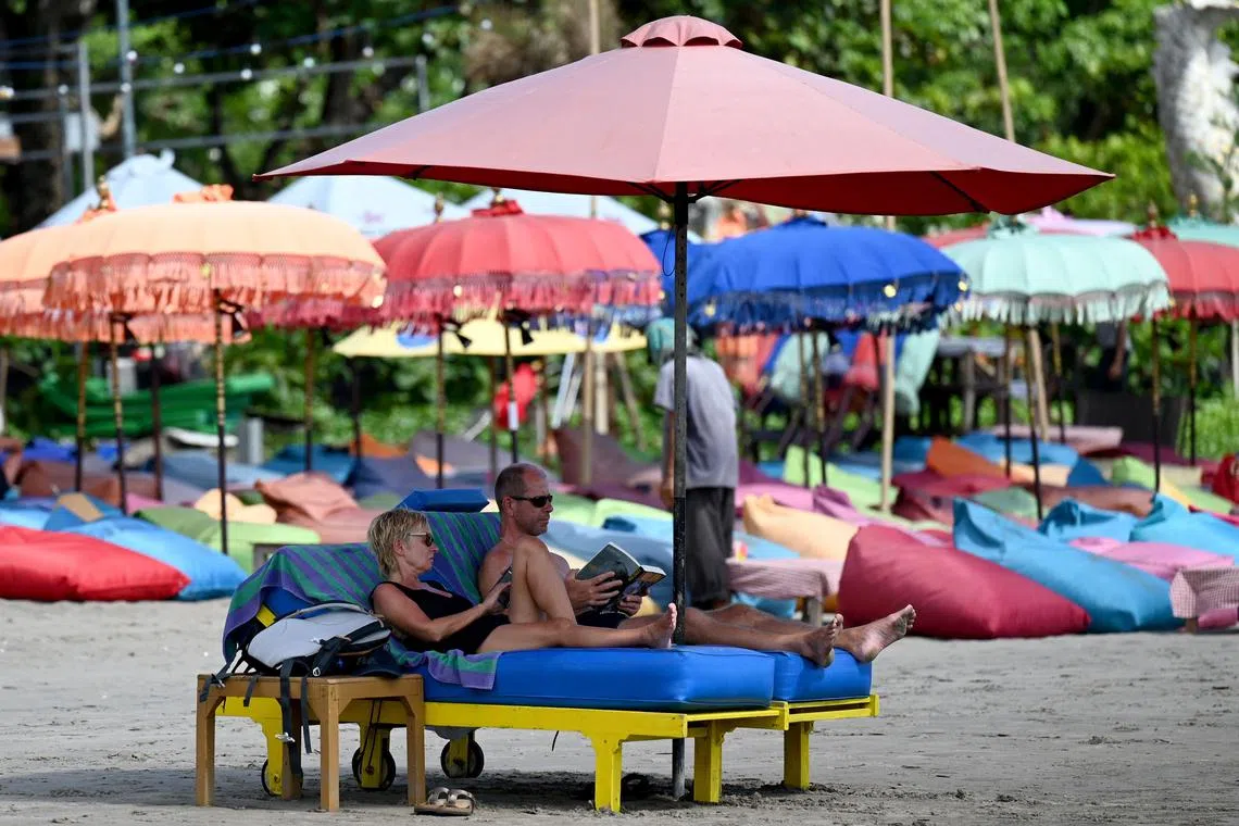 Foreign tourist lie on a beach in Seminyak, Badung regency on Indonesia resort island of Bali on December 7, 2022. (Photo by SONNY TUMBELAKA / AFP)