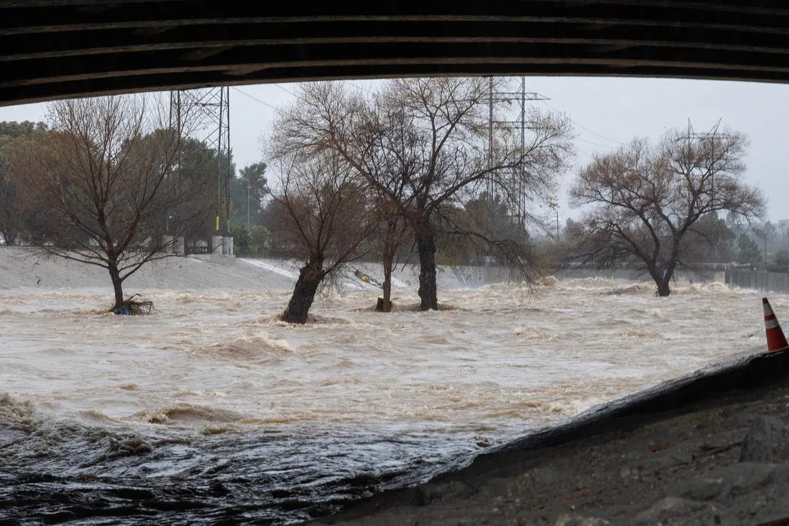 TOPSHOT - Water rages past a cart filled with items used by homeless people living along the Los Angeles River as the second and more powerful of two atmospheric river storms inundates Los Angeles, California, bringing record rainfall and flooding, on February 5, 2024. A powerful storm lashing California has killed at least one person, causing mudslides and flooding as Los Angeles experienced one of its wettest days ever. (Photo by Robyn Beck / AFP)