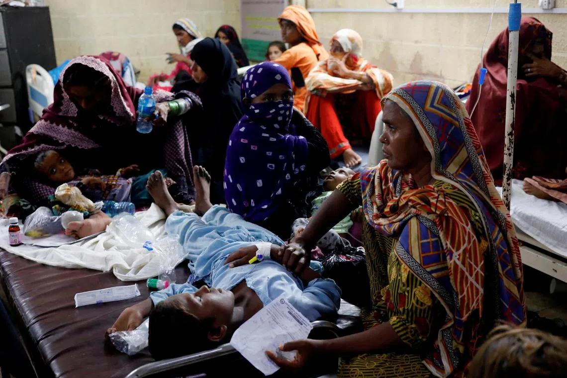 Women affected by the floods sit with their children suffering from malaria and fever, as they receive medical assistance at Sayed Abdullah Shah Institute of Medical Sciences in Sehwan, Pakistan September 29, 2022. REUTERS/Akhtar Soomro