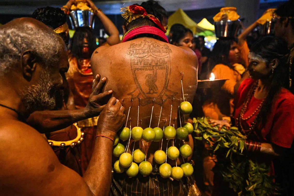 A Malaysian Hindu devotee in a state of trance has his back pierced with hooks before making his way towards the Batu Caves temple during the Thaipusam festival.