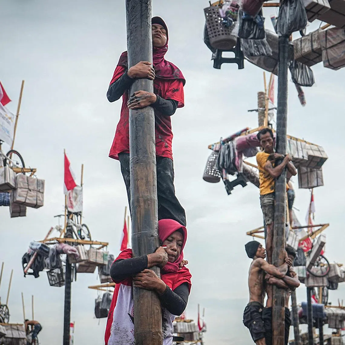 Women participate in a traditional game called "Panjat Pinang" to climb a 4-meter-high tree pole smeared with oil to collect prizes at the top as part of the annual celebration of Indonesia's 79th Independence Day in Palembang, South Sumatra, on August 18, 2024. (Photo by Al ZULKIFLI / AFP)